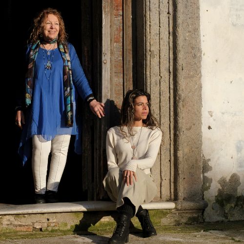 Two women who design fine sterling wholesale gemstone jewelry pose in the doorway of an Italian church. 
